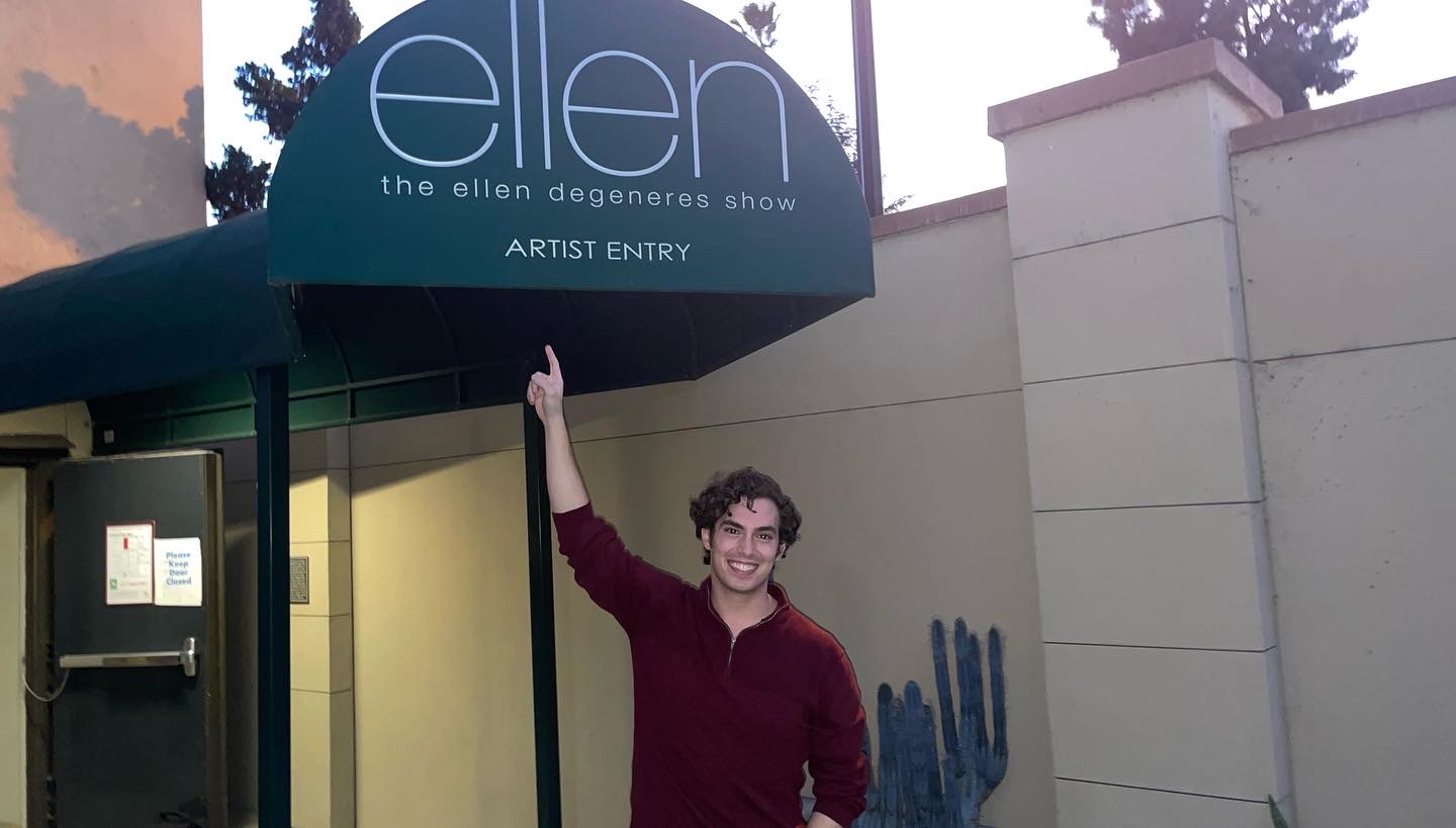 Neil under the Ellen DeGeneres Show "Artist Entry" sign at dusk, arm raised, big smile